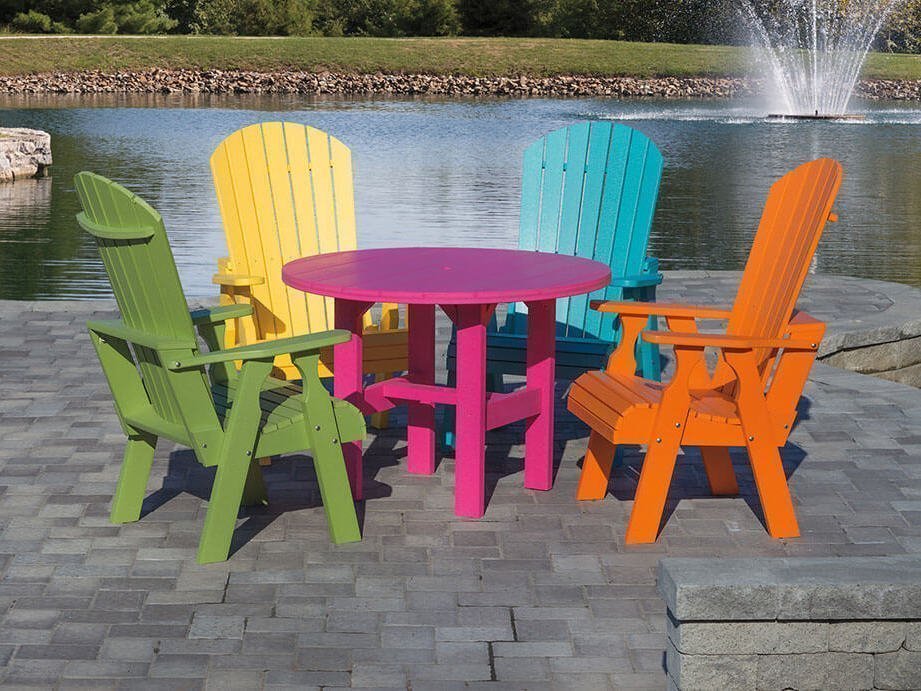 Fan back dining set bright colors Fan back Adirondack chairs in green, yellow, blue, and orange around a pink table.