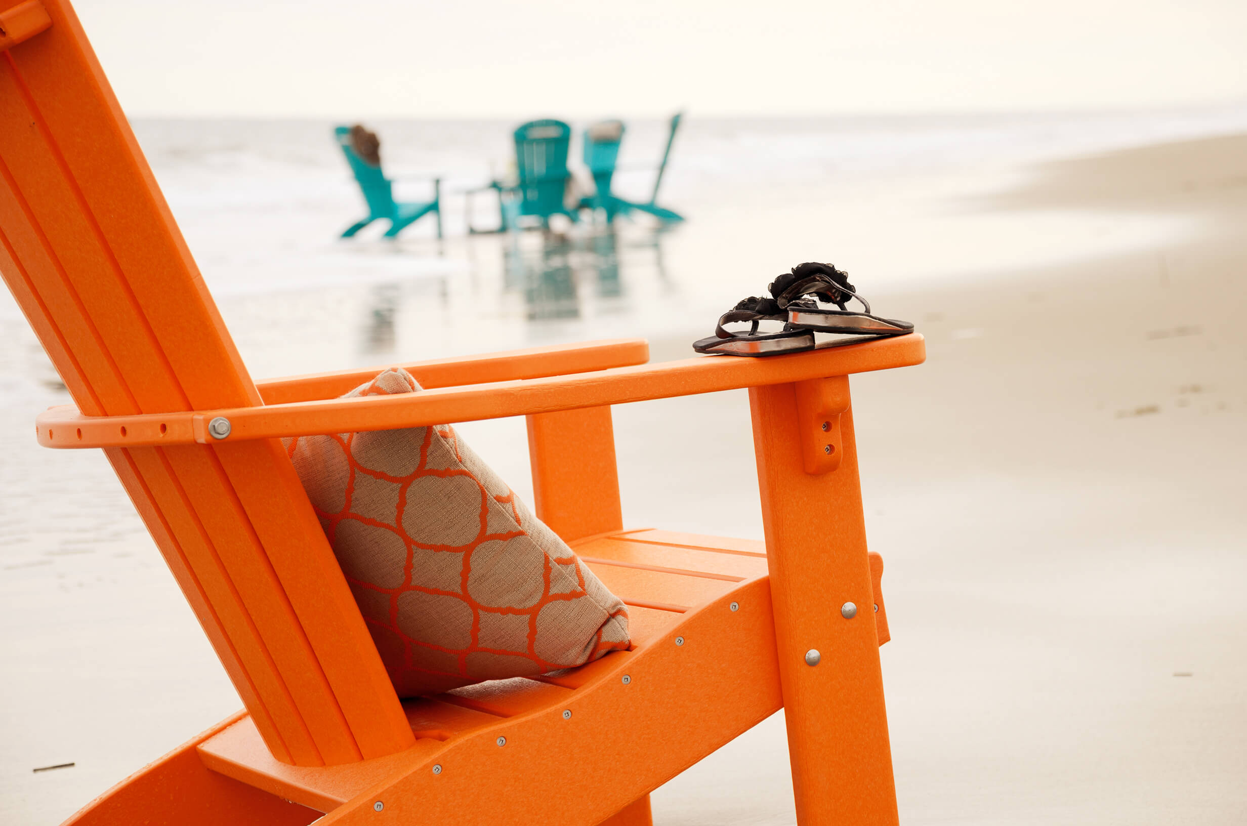 Adirondack chair Orange Adirondack chair on the beach.