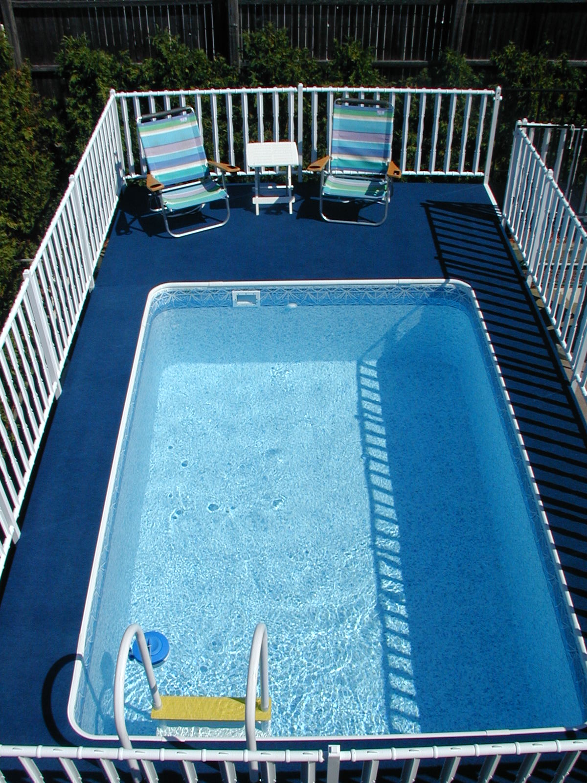 Admirals Walk Looking down onto a rectangle pool with deck and chairs.